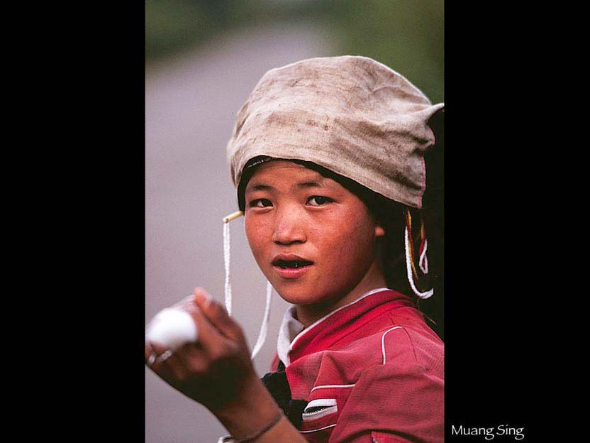 糸を紡ぎながら 家へと向かうアカ族の少女　ムアン・シン